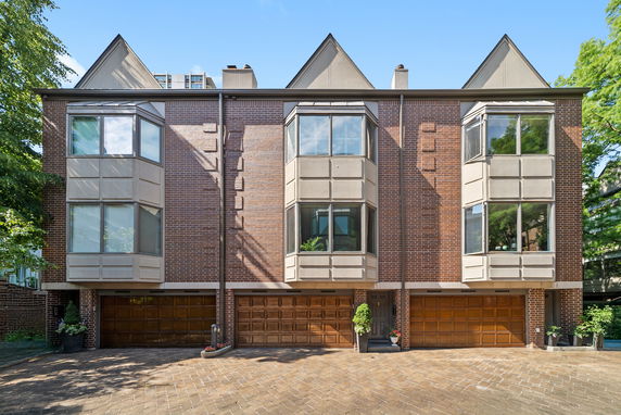 Front view of a brick townhouse with large bay windows and multiple garages.