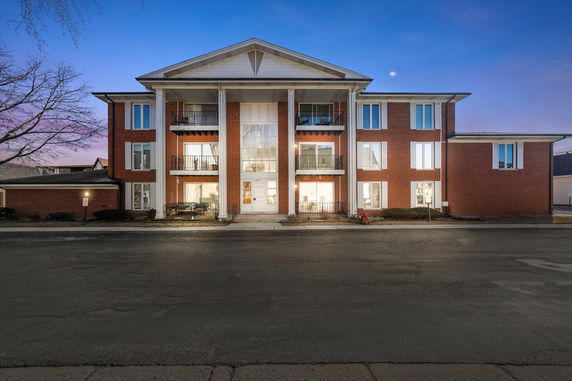Front view of a three-story brick building with large windows and balconies.