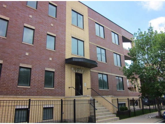 Front view of a multi-story brick building with multiple windows and a central entrance.