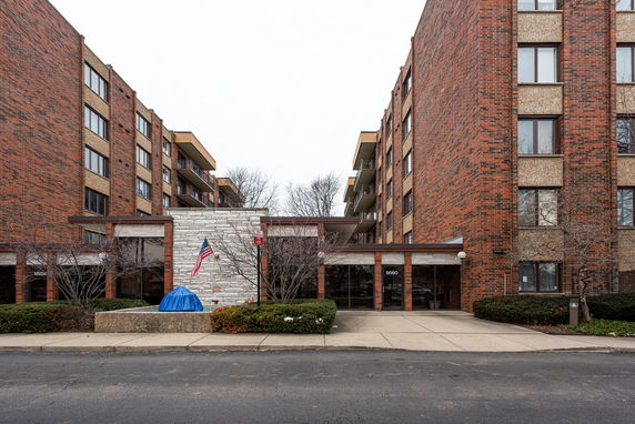 Front view of a multi-story brick building with a central entrance and balconies.