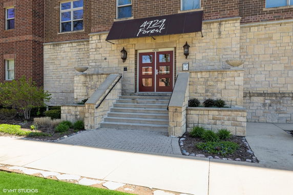 Front view of a building entrance with steps leading to double doors.
