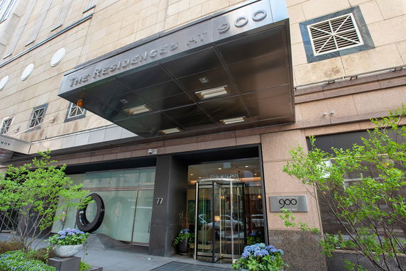 Front view of a residential building entrance with a covered entrance and glass doors.