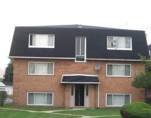 Front view of a two-story brick building with multiple windows and a black roof.