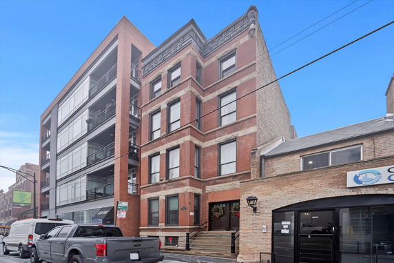 Front view of a multi-story brick building with large windows.