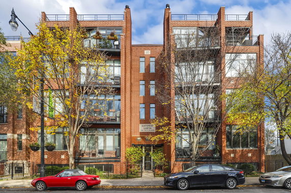 Front view of a multi-story brick apartment building with balconies.
