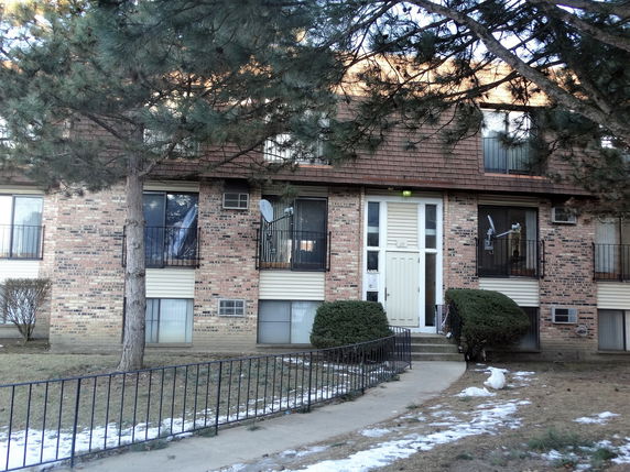 Front view of a two-story brick apartment building with balconies and a central entrance.