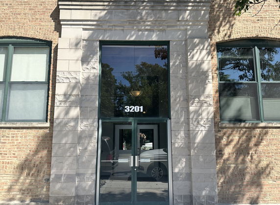 Front view of a building entrance with a glass door and two windows on either side.