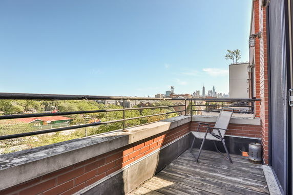 Balcony view showing distant city skyline with buildings under a clear blue sky.