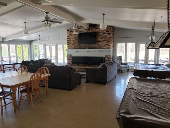 Recreational room with seating area, dining table, covered pool tables, and large windows.