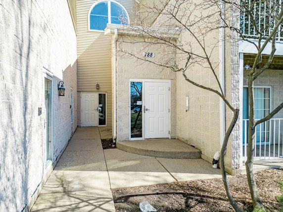 Entrance of a multi-story building with arched windows and light-colored walls.