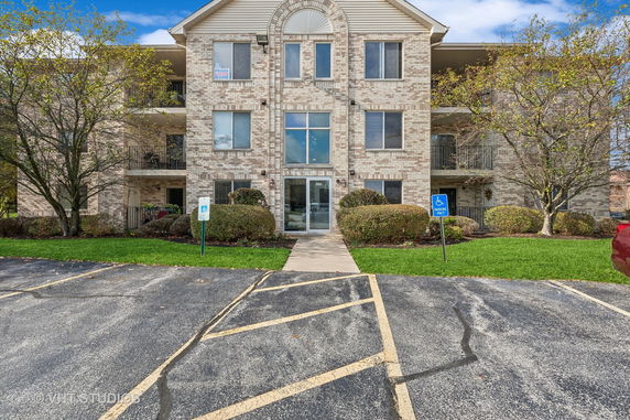Front view of a three-story apartment building with a brick facade and central entrance.