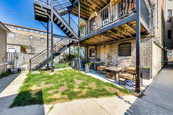 Elevated back view of a brick house with outdoor seating and metal staircase.