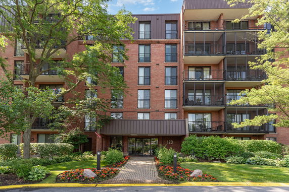 Front view of a multi-story brick apartment building with balconies.