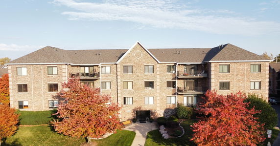 Front view of a three-story brick apartment building with balconies.