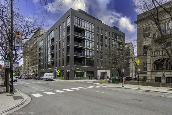 Front view of a modern multi-story building on a city street corner.