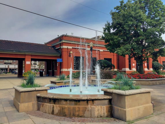 Front view of a red brick building with a fountain in front.