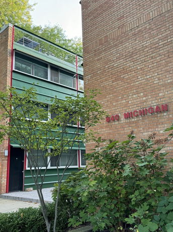 Front view of a multi-story building with a brick facade and green paneling.
