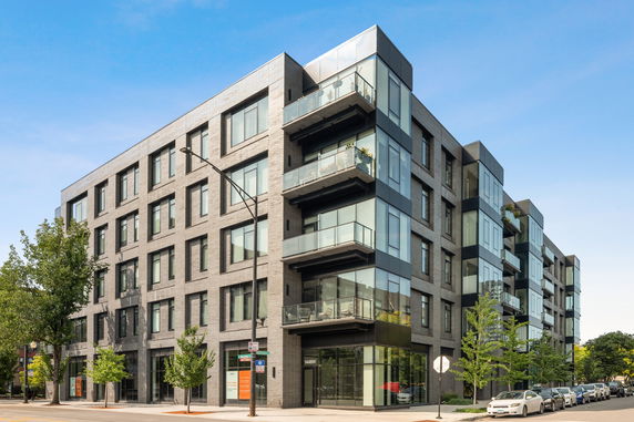 Front view of a multi-story apartment building with glass balconies.
