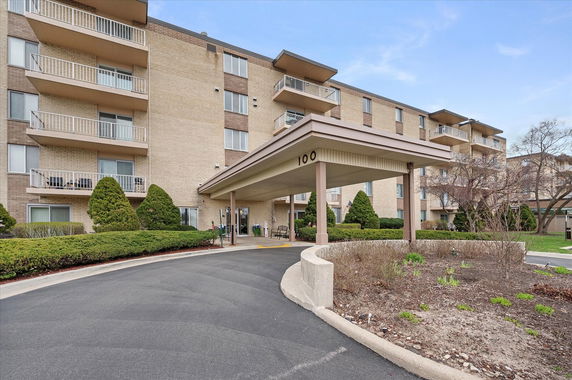 Front view of a multi-story residential building with balconies and a covered entrance.