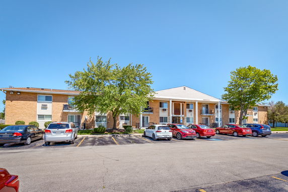 Front view of a two-story apartment building with multiple parked cars.