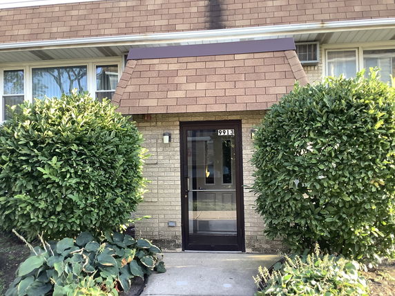 Front view of a house entrance with a brown shingled roof and brick exterior.