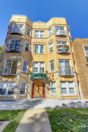 Front view of a multi-story brick apartment building with balconies