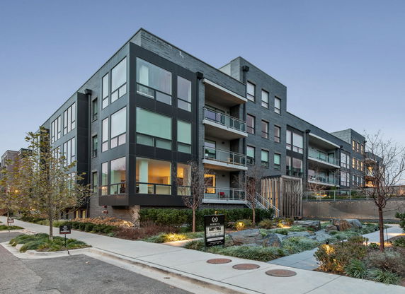 Front view of a multi-story apartment building with large windows and balconies.
