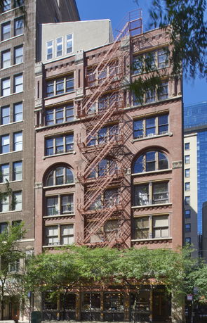 Front view of a multi-story brick building with fire escape stairs.