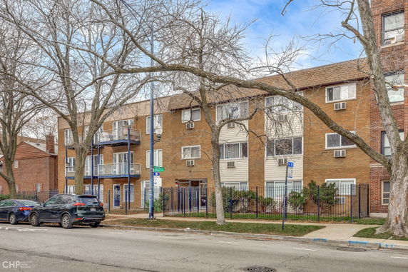 Front view of a multi-story apartment building with balconies and a brick facade.