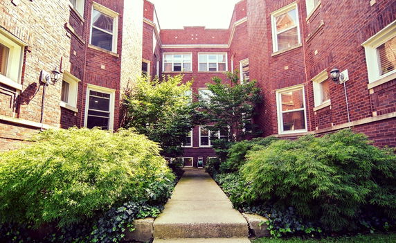 Front view of a brick multi-story building with multiple windows.