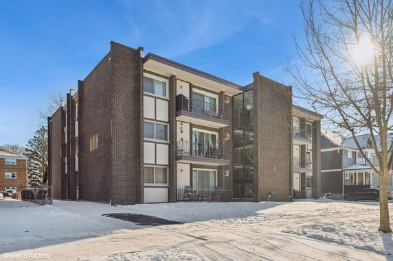 Front view of a multi-story brick apartment building with balconies.