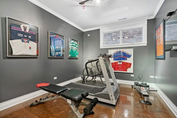 Interior view of a home gym with exercise equipment and sports jerseys on the walls.