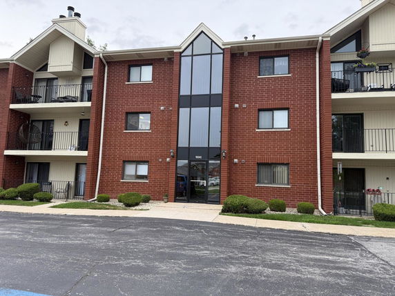 Front view of a multi-story apartment building with red brick and balconies.