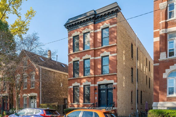 Front view of a three-story brick building with decorative architectural details and multiple windows.