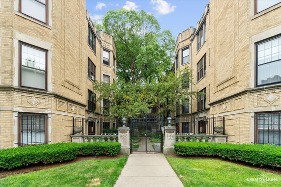 Front view of a multi-story brick building with a central courtyard entrance.