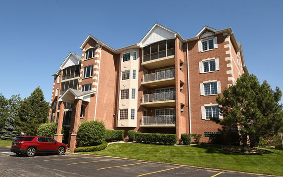 Front view of a multi-story brick building with balconies and parking area.