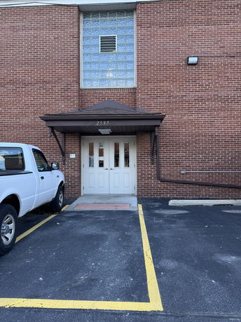 Front view of a brick building with a brown awning over a set of double doors.
