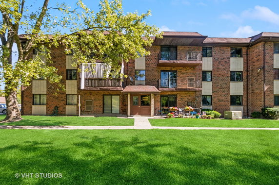 Front view of a three-story brick apartment building with balconies.