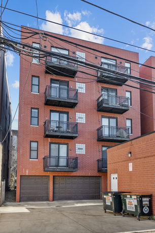 Front view of a multi-story brick building with balconies and garage doors.