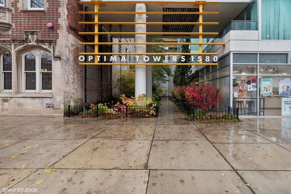 Front view of a modern building with a glass facade and brick detailing, featuring Optima Towers signage.