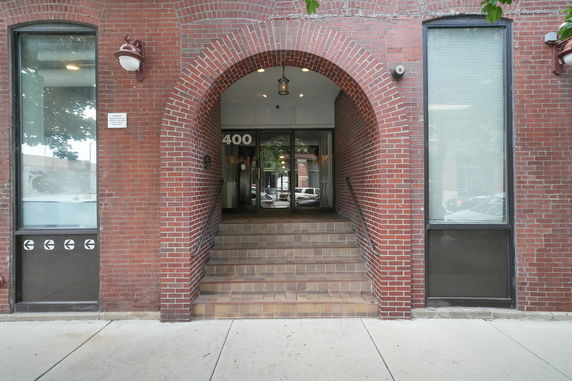 Front view of a brick building entrance with a rounded arch.