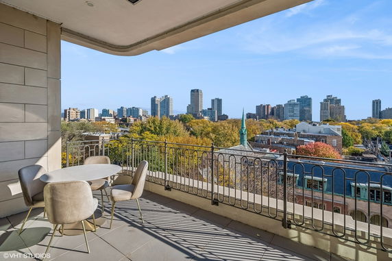 Outdoor balcony view showing a cityscape with tall buildings and trees.