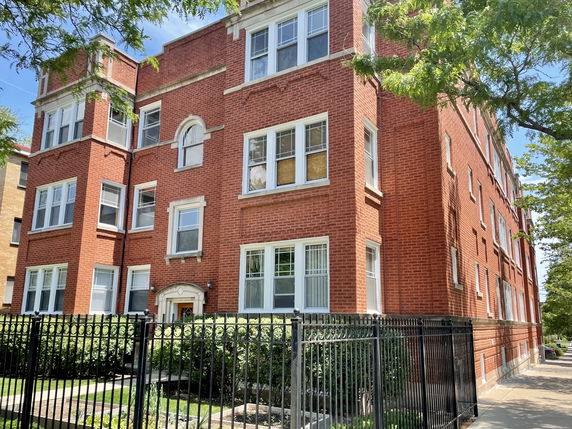Front view of a red brick apartment building with multiple stories.