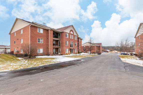 Front view of a multi-story brick apartment building with balconies.