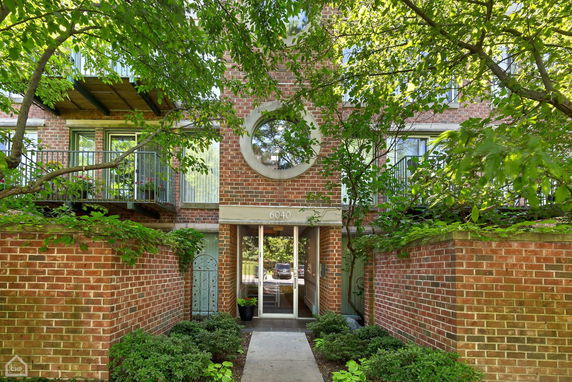 Front view of a brick residential building with balconies and a circular window.