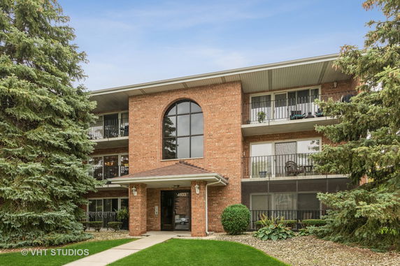 Front view of a three-story brick apartment building with balconies.