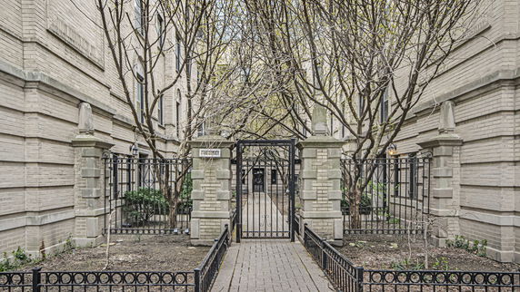 Entrance view of a brick apartment building with a gated pathway.