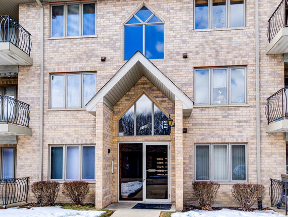 Front view of a multi-story brick apartment building with balconies.