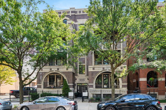 Front view of a multi-story brick building with arched windows and balconies.