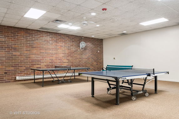 Room with a table tennis setup against a brick wall.